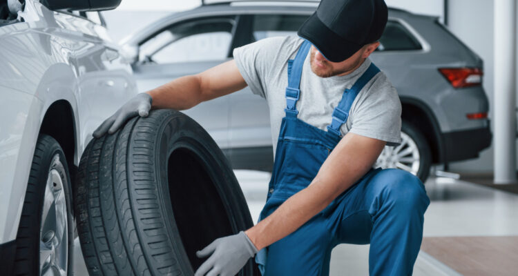 fresh-material-mechanic-holding-a-tire-at-the-repair-garage-replacement-of-winter-and-summer-tires