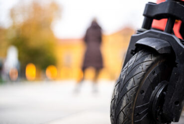 closeup-shot-of-a-wheel-of-a-motorcycle-with-a-person-standing-in-the-back